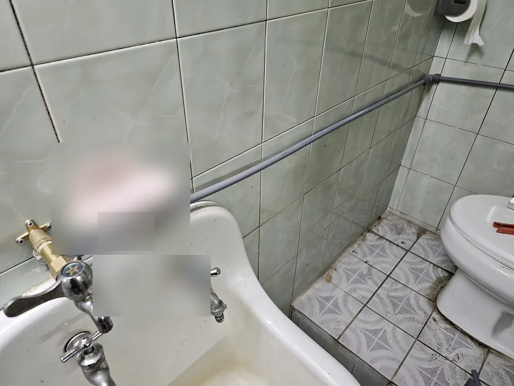 세면대 위 타일 벽을 따라 지나가는 새 회색 급수관