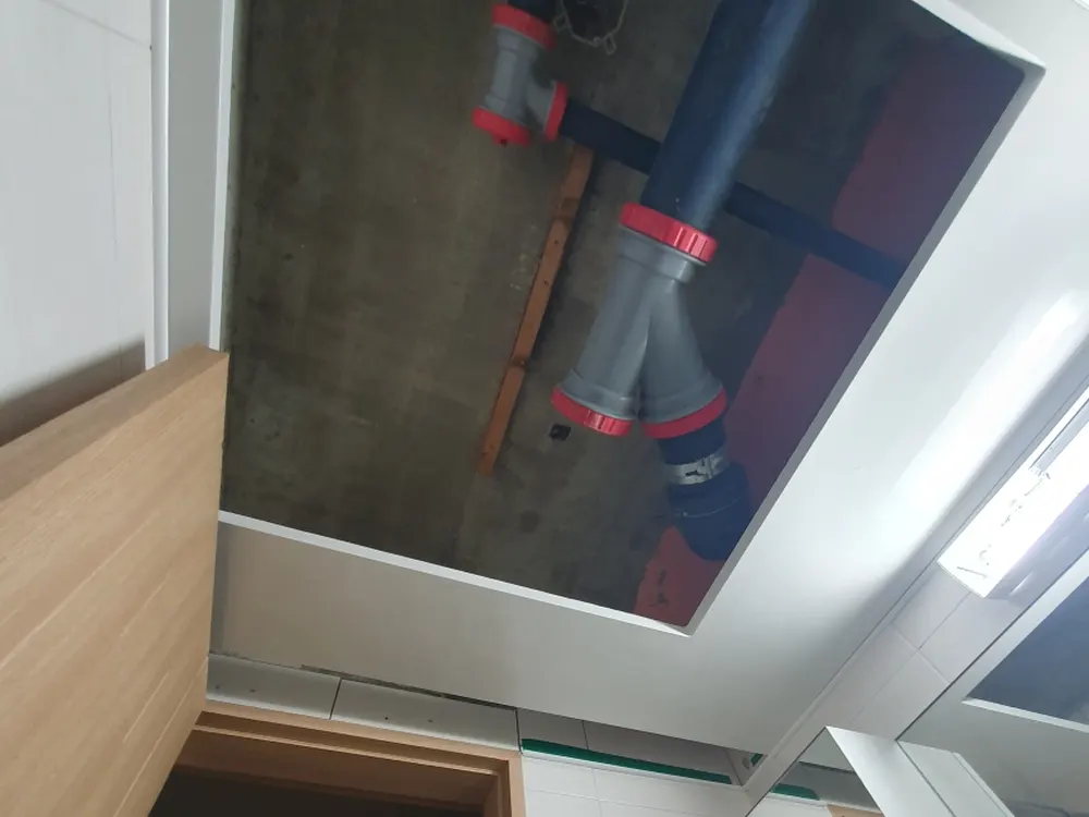 문 쪽에서 올려다본 열린 천장 점검구와 속의 회색 배관